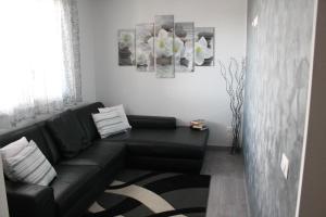 uma sala de estar com um sofá preto e algumas fotografias em B&B LA VILLETTA em Macerata Campania