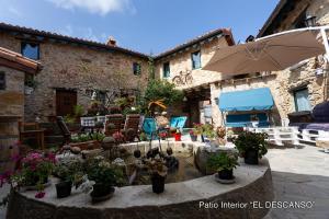 a patio with potted plants and an umbrella at El Valle Perdido Casas Rurales in Revelillas