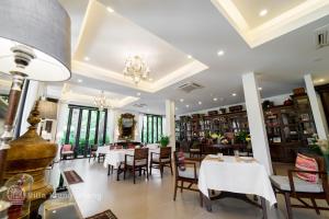 restauracja z białymi stołami, krzesłami i oknami w obiekcie Villa Klang Wiang w mieście Chiang Mai