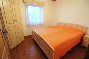 a bedroom with an orange bed and a window at Vineyard Cottage Stepan in Črnomelj
