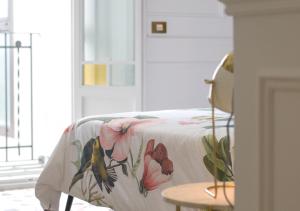 a bed with a floral blanket on it with a table at Casa Timoteo Apartamentos Boutique Adults Only in Alcoy