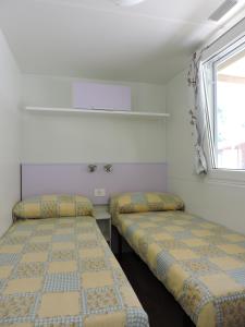 two beds in a small room with a window at Camping Reno in Casal Borsetti