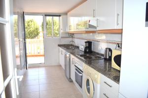 a kitchen with white cabinets and a stove top oven at Apartamento Nou Fontana in Jávea