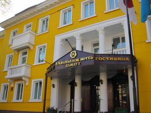 um edifício amarelo com um sinal em frente em Ambassador em Almaty