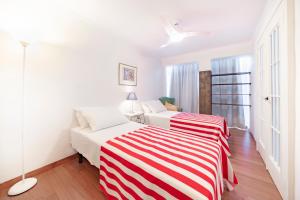 ネルハにあるApartamento En El Centro De Nerjaの白い部屋のベッド2台(赤と白のストライプ毛布付)