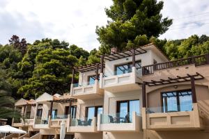a large building with balconies and trees in the background at Blue Green Bay in Panormos Skopelos