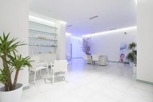 a white room with white tables and chairs and a plant at Hotel Parco Smeraldo Terme in Ischia