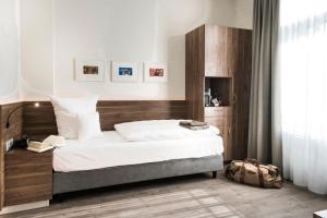 a bedroom with a large bed with a wooden headboard at Alexianer Hotel am Wasserturm in Münster