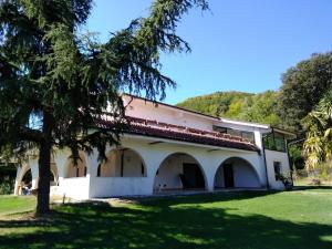 un grand bâtiment blanc avec un arbre au premier plan dans l'établissement "CARA PACE" in collina per famiglie, à Montefiore Conca
