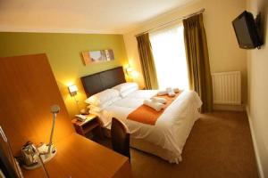 a hotel room with a bed and a desk at Rose And Crown in Porthcawl