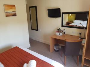 a bedroom with a desk and a bed and a mirror at Rose And Crown in Porthcawl