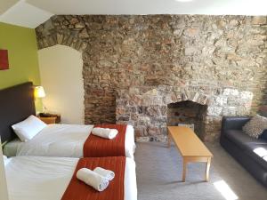 a hotel room with two beds and a stone wall at Rose And Crown in Porthcawl