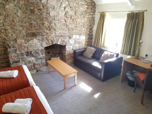 a living room with a couch and a stone wall at Rose And Crown in Porthcawl