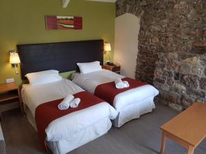 a hotel room with two beds and a stone wall at Rose And Crown in Porthcawl