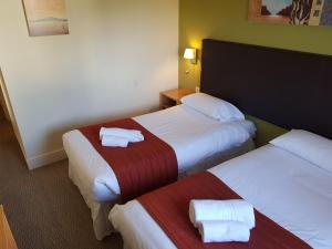 a hotel room with two beds with towels on them at Rose And Crown in Porthcawl
