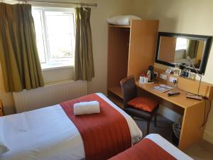 a hotel room with a bed and a desk with a computer at Rose And Crown in Porthcawl