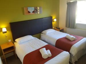 a hotel room with two beds with towels on them at Rose And Crown in Porthcawl