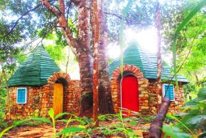 a small stone house with a red door in the forest at Phu Nam House - Resort in Phú Quốc