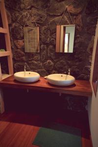 a bathroom with two sinks and a stone wall at La Kaz Nana Sakifo - Maison d'hotes in Saint-Paul +39 photos