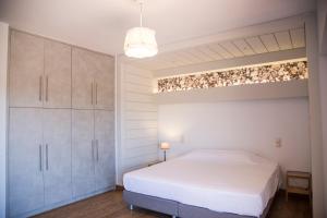 um quarto com uma grande cama branca e armários em Mediterra retreat em Kapandrítion