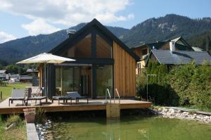 a house on a dock in the water with an umbrella at dasGams in Gosau