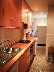 uma cozinha com armários de madeira, um lavatório e um frigorífico em Apartamentos Torr Av América - López de Hoyos - Chamartín em Madri