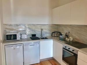 波尔图Sé Boutique Apartment的厨房配有白色橱柜、水槽和微波炉 更多18张照片