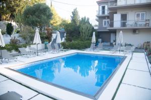 a swimming pool with chairs and umbrellas next to a building at Pessada Bay Studios and Apartments in Pesádha