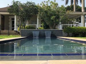 a swimming pool with a fountain in front of a house at The Bentley Westville in Durban