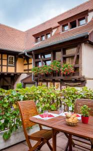 Une table et des chaises en bois sont disponibles sur la terrasse. dans l'établissement La Cour du Bailli Suites & Spa, à Bergheim