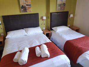 two beds in a hotel room with white towels on them at Rose And Crown in Porthcawl