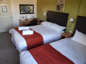 a hotel room with two beds and a desk at Rose And Crown in Porthcawl