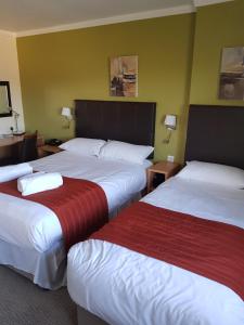 a hotel room with two beds with red and white sheets at Rose And Crown in Porthcawl