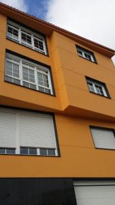 a yellow building with white windows at PISO HARLEY in Camariñas
