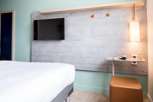 a bedroom with a bed and a tv on a wall at ibis budget Paris Gennevilliers in Gennevilliers