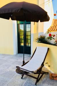 a lounge chair with an umbrella in front of a building at casadaeiradeangeja in Angeja