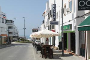 a street with tables and umbrellas on a city street at Hostal El Yunque in Conil de la Frontera +29 photos