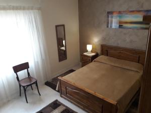 1 dormitorio con cama, silla y espejo en Grazzja Traditional Apartment, en Żabbar