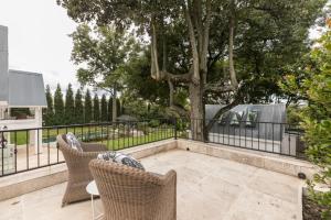 a patio with two chairs and a fence and a tree at Oxford Healthcare Retreat in Johannesburg