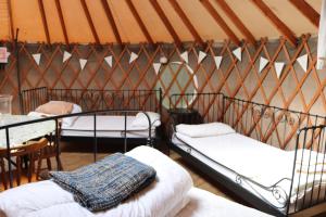 two beds in a tent with a table and chairs at Yurtcamp Devon in Newton Abbot