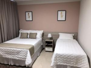 a bedroom with two beds and a night stand at Hotel San Remo in Jequié