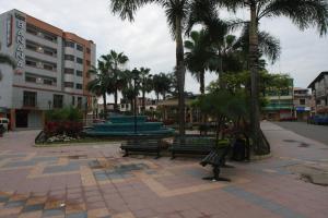 a park with benches and palm trees in a city at Hotel Puerto Banana in El Guabo