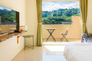 a bedroom with a bed and a large window at Cozy Green Guesthouse in Taitung City