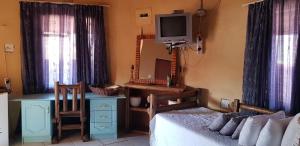 Un dormitorio con una cama, un escritorio y un televisor. en Gae Lodge, en Ganyesa