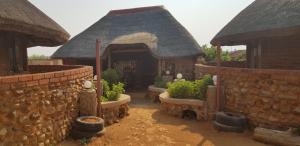 una casa con una pared de piedra y algunas plantas en Gae Lodge, en Ganyesa