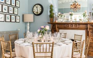 a table in a room with a clock on the wall at Didsbury House Hotel in Manchester