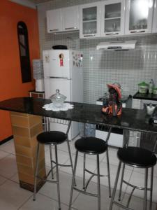 a kitchen with a counter and three bar stools at Casa da Ú in Lençóis