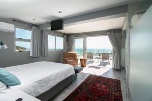 een slaapkamer met een bed en uitzicht op de oceaan bij Bikini Beach Penthouse in Gordonsbaai