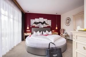 a bedroom with a large white bed with a red wall at ... mein romantisches Hotel Toalstock in Fiss