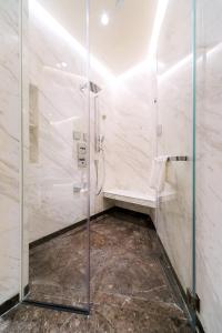 a bathroom with a glass shower with a bench at AKVO Hotel in Hong Kong